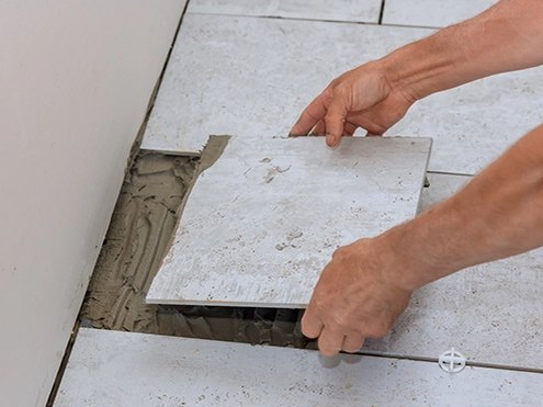 Setting a floor tile into fresh thinset mortar