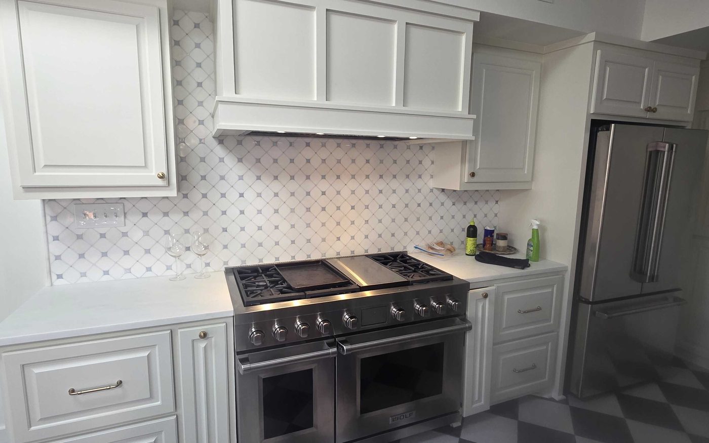 Finished kitchen with white cabinets, a range hood and a tile backsplash