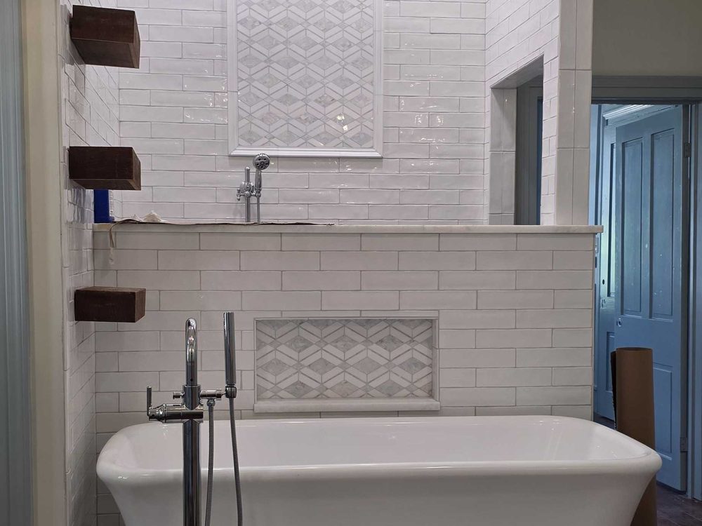 Freestanding tub on a tile pad in front of a white subway tile shower